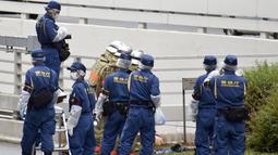 Polisi dan petugas pemadam kebakaran memeriksa tempat kejadian di mana seorang pria dilaporkan membakar dirinya sendiri, di dekat Kantor Perdana Menteri di Tokyo, Rabu, 21 September 2022. Saat ini pria tersebut dalam keadaan tak sadar. Sementara itu, seorang petugas kepolisian yang sempat berupaya memadamkan api juga terluka. (Kyodo News via AP)