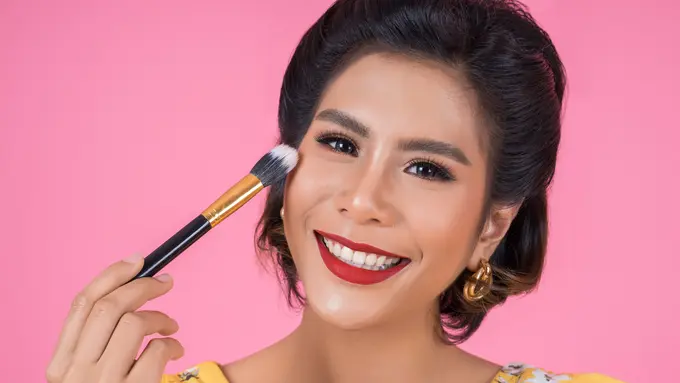Seorang perempuan sedang tersenyum sambil memegang sebuah brush (Foto Dok: Freepik/jcomp)