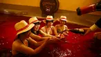Seorang pria menuangkan anggur ke dalam tangan seorang wanita saat mereka duduk dalam air panas dengan air berwarna anggur di resor spa Hakone Kowaki-en Yunessun saat acara menandai Beaujolais Nouveau Day,Tokyo, Jepang (19/11). (REUTERS/Thomas Peter)