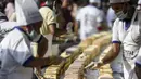 Pembuat roti dan koki menyelesaikan kue sepanjang 6,5 km untuk kue terpanjang dunia, di Thrissur di negara bagian Kerala, India selatan (15/1/2020). Dibutuhkan 12 ribu kilogram gula dan tepung dan menghabiskan waktu lebih dari empat jam untuk membuat kue terpanjang itu. (AFP/Arun Sankar)