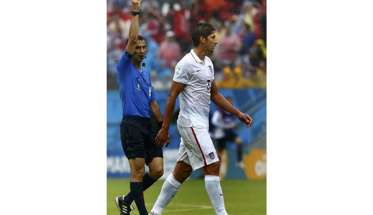 Pemain belakang AS, Omar Gonzalez (kanan) harus menerima kartu kuning dari wasit Ravshan Irmatov di laga penutup penyisihan Piala Dunia 2014 Grup G di Stadion Pernambuco, Recife, Brasil, (26/6/2014). (REUTERS/Tony Gentile)  