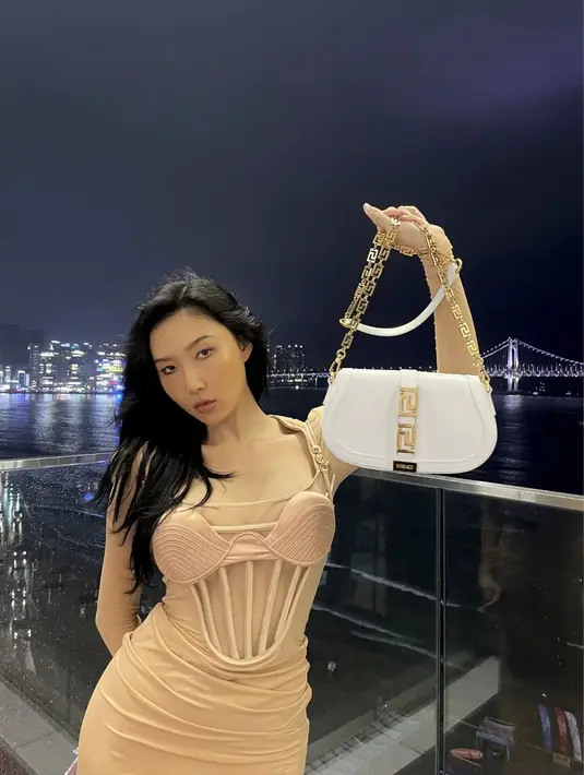 Hwasa terlihat elegan dengan dress bustier transparan dari Versace berwarna nude. Dipadukan dengan shoulder bag Versace berwarna putih [@_mariahwasa]