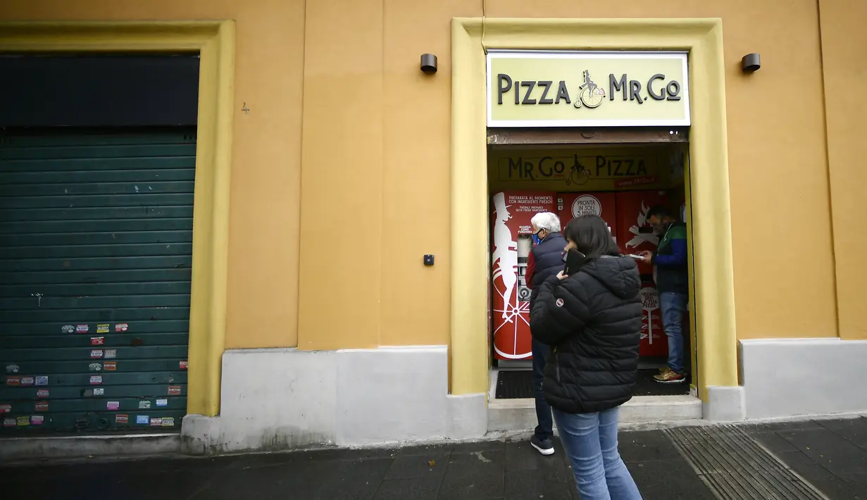 Orang-orang mengantre di mesin penjual pizza otomatis, yang pertama dari jenisnya di pusat kota Roma, Italia pada 29 April 2021. Mesin penjual otomatis ini mampu menguleni adonan, membumbui, memasak, dan menyajikan pizza dalam kotak karton hanya dalam waktu tiga menit. (Filippo MONTEFORTE/AFP)
