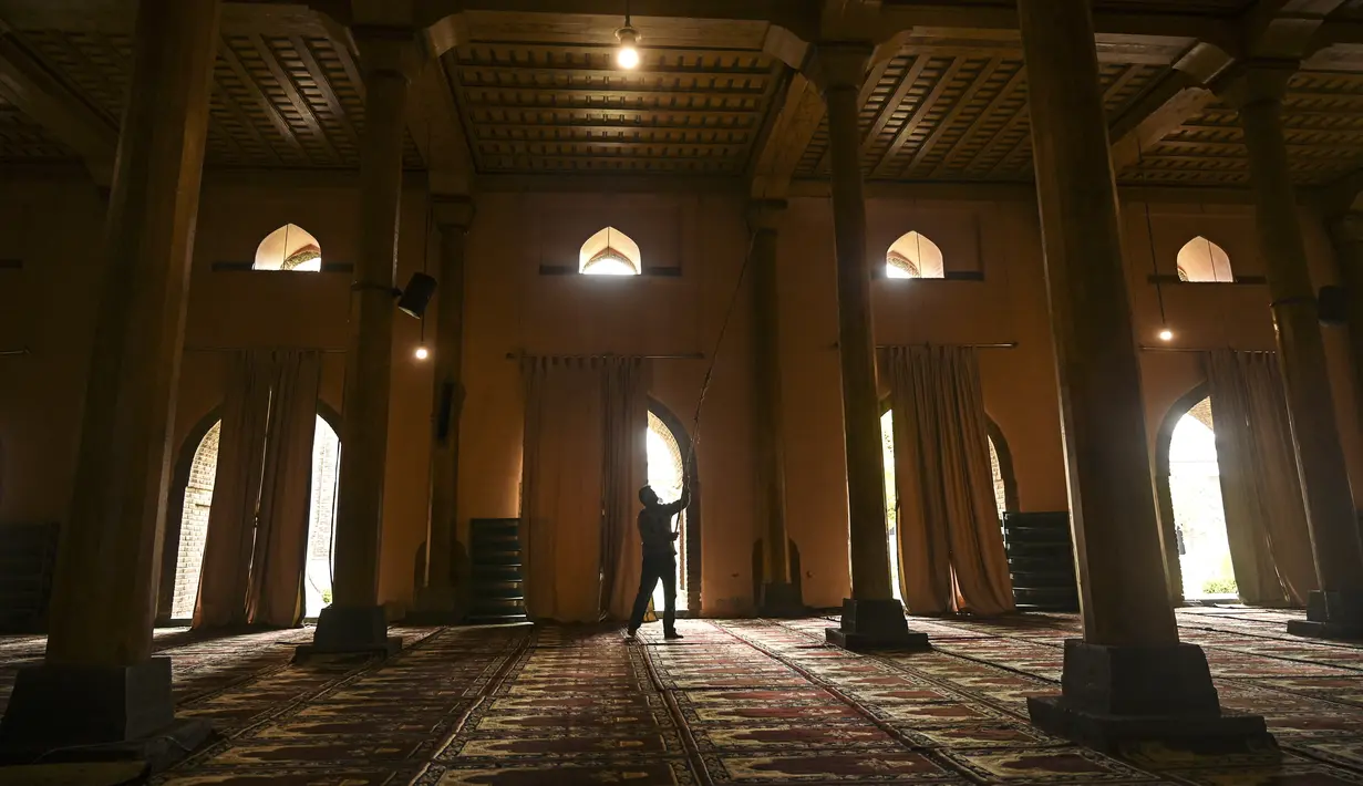 Seorang pria membersihkan langit-langit masjid Jamia selama bulan suci Ramadhan di Srinagar (20/4/2021). Masjid ini terletak di pusat kota yang tetap menjadi zona sentral kehidupan politik-agama di Srinagar. (AFP/ Tauseef Mustafa)
