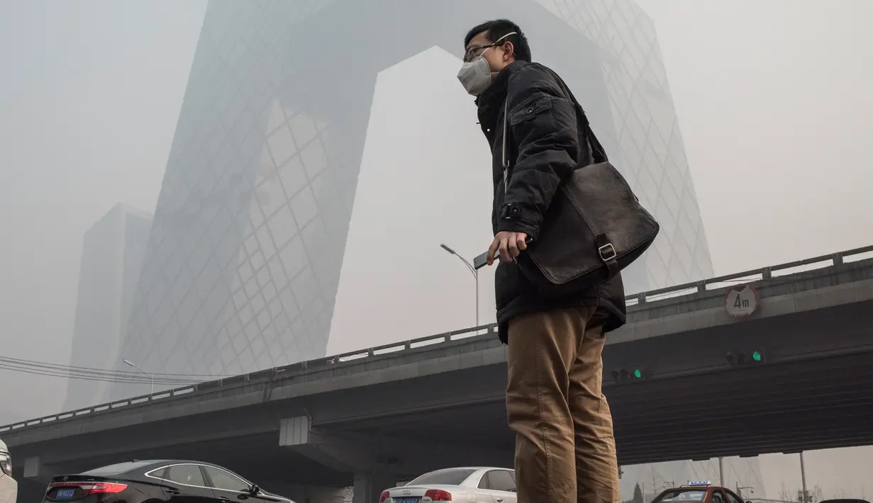Warga mengenakan masker saat kabut asap menyelimuti Beijing, China, Senin (30/11). Pemerintah setempat mengumumkan keadaan siaga dan menyarankan warga Beijing untuk berada dalam rumah karena kandungan polusi udara yang berbahaya. (AFP PHOTO/ FRED DUFOUR)