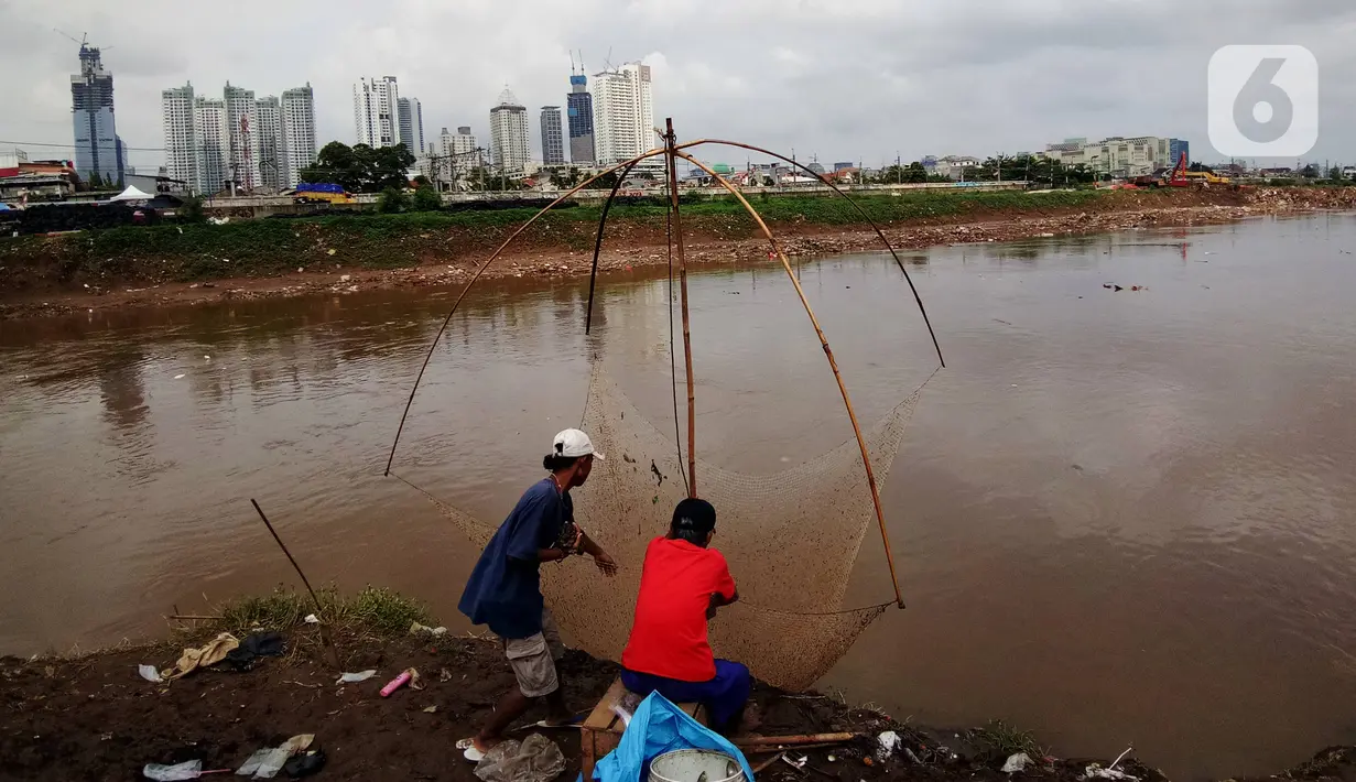 Warga menarik jala ikan dari tepi Banjir Kanal Barat, Tanah abang, Jakarta, Sabtu (4/1/2020). Debit air yang mulai surut di aliran tersebut dimanfaatkan warga untuk mencari ikan. (Liputan6.com/Angga Yuniar)