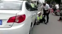 Seorang petugas polisi lalu lintas berpura-pura merintis kesakitan di aspal. (shanghaiist)