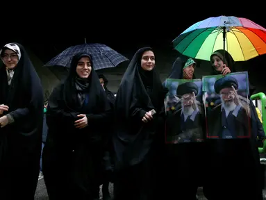 Perempuan Iran membawa poster Ayatollah Ali Khamenei saat memperingati 40 tahun Revolusi Islam Iran di Teheran, Senin (11/2). Ratusan ribu orang mengikuti peringatan 40 tahun Revolusi Islam Iran. (AP Photo/Ebrahim Noroozi)