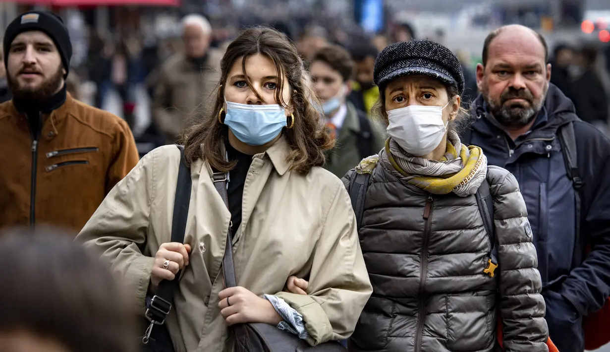 Orang-orang dengan masker melintasi jalan di pusat kota Amsterdam, Belanda, Rabu (3/11/2021). Belanda kembali menerapkan tindakan pembatasan virus corona, termasuk kewajiban memakai masker di berbagai ruang publik menyusul lonjakan kasus Covid-19 beberapa waktu terakhir. (Ramon van Flymen/ANP/AFP)