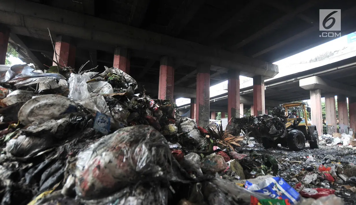Petugas PPSU menggunakan alat berat mengangkut sampah di kolong Tol Wiyoto-Wiyono, Sungai Bambu, Jakarta, Selasa (15/1). Dalam sehari petugas kebersihan mengangkut sampah hingga 10 truk dengan berat total sekitar 100 ton. (Merdeka.com/Iqbal S. Nugroho)