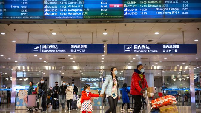 Penerbangan dari Wuhan Ditutup:  Pelancong berjalan melintasi papan informasi tentang penerbangan dari Wuhan telah dibatalkan di Bandara Internasional Ibu Kota Beijing pada Kamis (23/1/2020). China menangguhkan semua transportasi dari dan ke kota pusat penyebaran virus corona. (AP/Mark Schiefelbein)