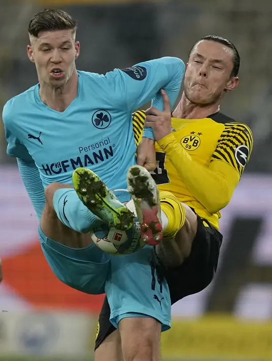 Penyerang Greuther Fuerth Cedric Itten berebut bola dengan bek Borussia Dortmund Nico Schulz pada laga pekan ke-16 Bundesliga di Signal Iduna Park, Kamis (16/12/2021) dini hari WIB. Borussia Dortmund mampu meraih kemenangan 3-0 atas Greuther Fuerth. (AP Photo/Martin Meissner)