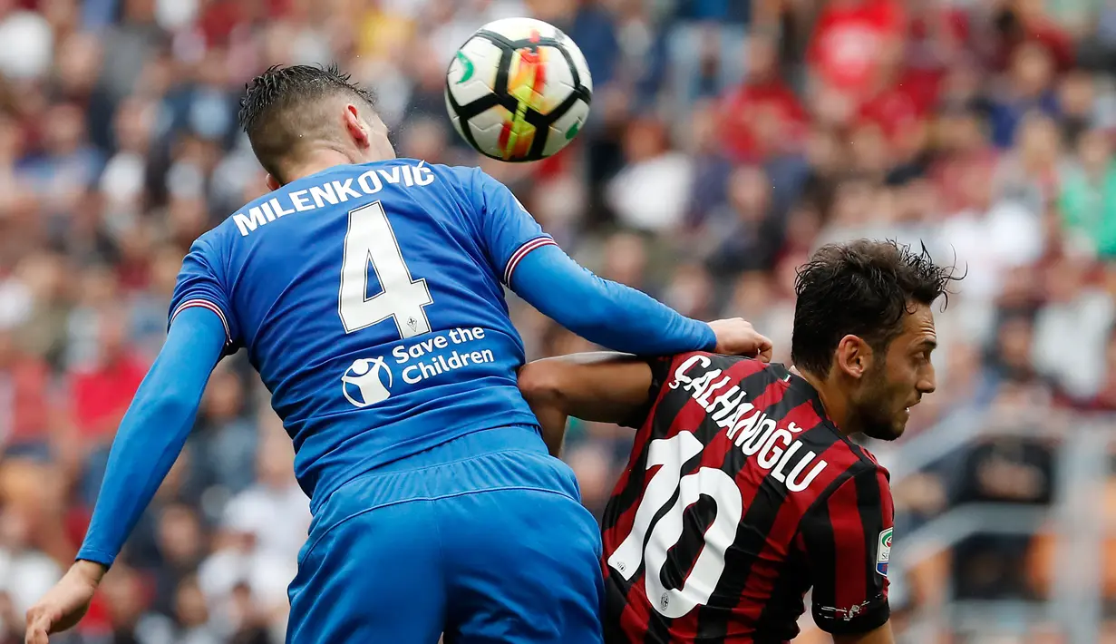 Gelandang AC Milan, Hakan Calhanoglu berebut bola udara dengan pemain Fiorentina Nikola Milenkovic pada lanjutan Liga Serie A Italia di stadion San Siro (20/5). Calhanoglu mencetak satu gol di pertandingan tersebut. (AP Photo/Antonio Calanni)