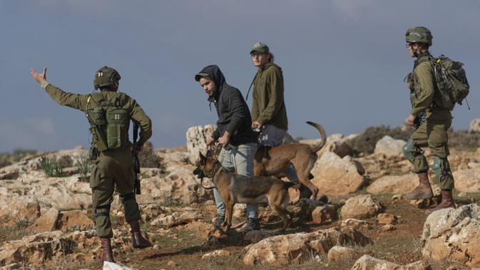 Pemukim Yahudi menggunakan anjing saat bentrok dengan pengunjuk rasa Palestina di Desa Mughayer, Ramallah, Tepi Barat, Jumat (18/12/2020). Pengunjuk rasa Palestina yang menggunakan ketapel terlibat bentrok dengan pemukim Yahudi yang menggunakan anjing. (AP Photo/Nasser Nasser)