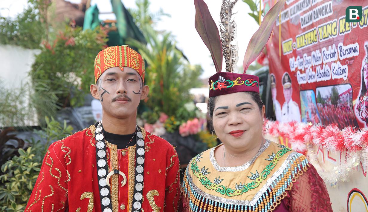 Pasangan pria dan wanita dengan pakaian adat Kalimantan Tengah berpose dalam rangkaian acara Festival Budaya Isen Mulang di Bundaran Palangkaraya, Minggu (19/5/24) pagi. (Bola.com/Ade Yusuf Satria)