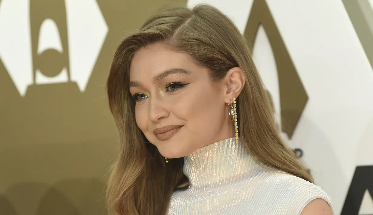 Gigi Hadid tersenyum saat tiba menghadiri CMA Awards tahunan ke-53 di Bridgestone Arena di Nashville, Tennessee (13/11/2019). Model berusia 24 tahun ini tampil memukau dalam balutan gaun putih. (AP Photo/Evan Agostini)