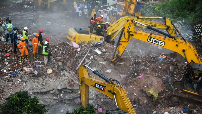 Petugas penyelamat mencari korban di reruntuhan gedung apartemen yang runtuh di Mahad, India (25/8/2020). Sedikitnya 50 orang terjebak dalam semalam di dalam apartemen yang runtuh tersebut. (AFP Photo/Punit Paranjpe)
