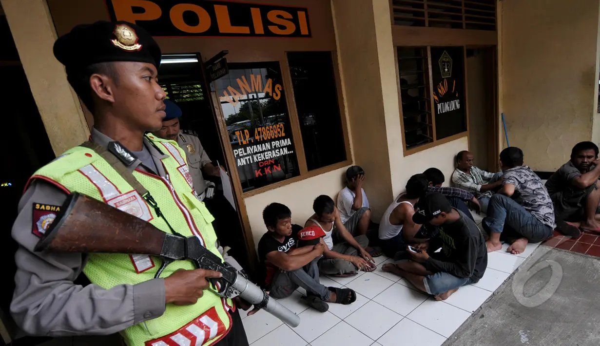 Petugas polisi berjaga mengamankan sejumlah preman di kawasan terminal Pulogadung, Jakarta, Kamis, (12/3/2015). Petugas berhasil menyita minuman keras, senjata tajam, dan belasan orang yang diduga preman di lokasi tersebut. (Liputan6.com/Johan Tallo)