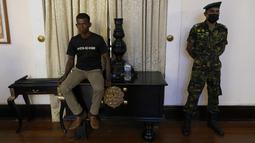 Perwira Angkatan Darat Sri Lanka berjaga-jaga ketika pengunjuk rasa duduk di atas meja di kediaman resmi presiden Gotabaya Rajapaksa di Kolombo, Rabu (13/7/2022). Presiden Sri Lanka Gotabaya Rajapaksa melarikan diri ke Maladewa menjelang pengumuman pengunduran dirinya hari ini, setelah berbulan-bulan aksi protes yang meluas terhadap krisis ekonomi terburuk negara pulau itu. (AP Photo/Rafiq Maqbool)