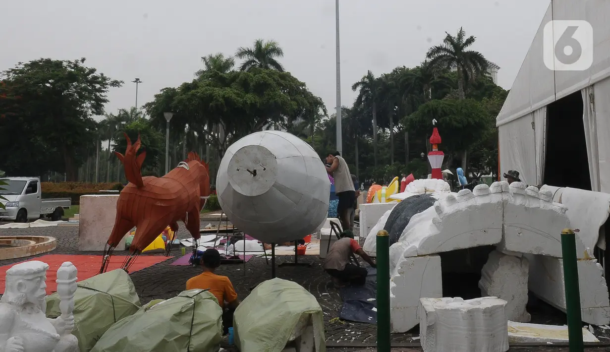 Pekerja seni menyelesaikan pembuatan patung untuk mobil hias di Silang Monas, Jakarta, Selasa (26/12/2023). (merdeka.com/Imam Buhori)