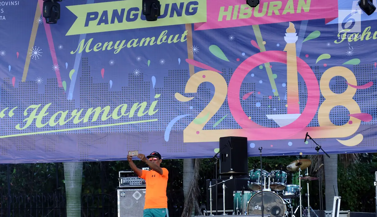 Warga berswafoto di panggung utama perayaan malam pergantian tahun di kawasan Bundaran HI, Jakarta, Minggu (31/12). Pemprov DKI menetapkan Bundaran HI sebagai lokasi berdirinya panggung utama malam perayaan tahun baru. (Liputan6.com/Helmi Fithriansyah)