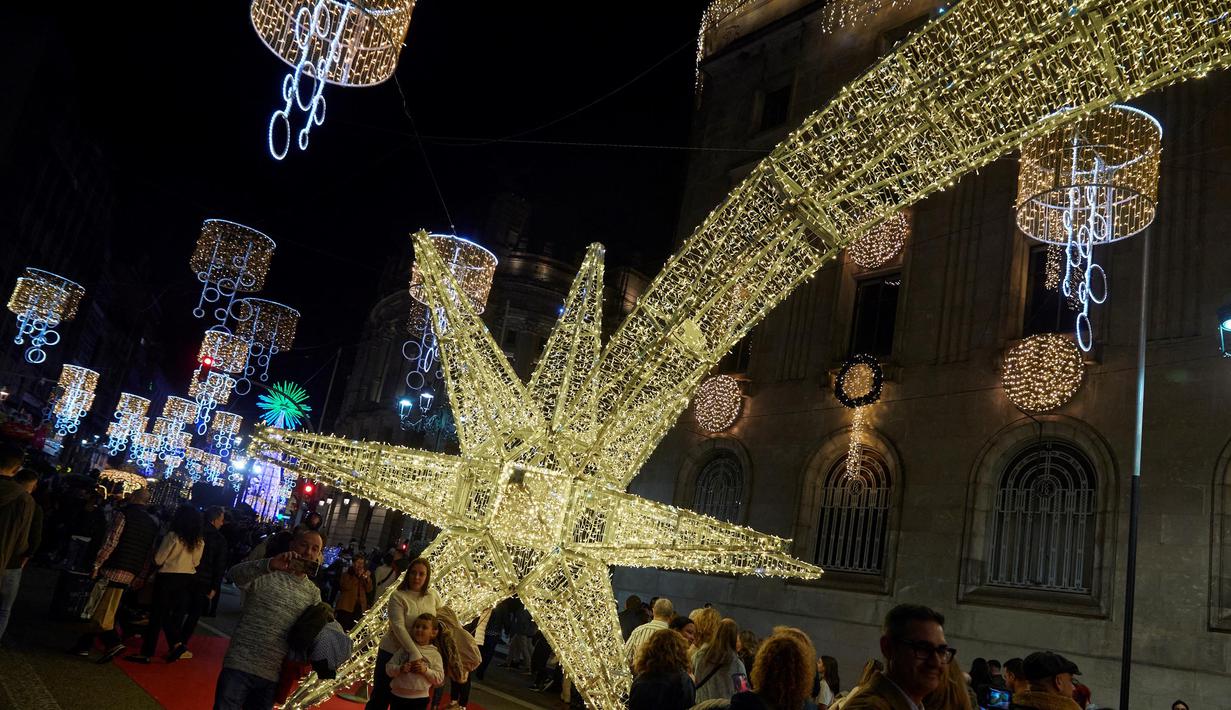 Orang-orang berfoto di bawah lampu-lampu Natal di pusat kota Vigo, barat laut Spanyol, pada 16 November 2024. (MIGUEL RIOPA/AFP)
