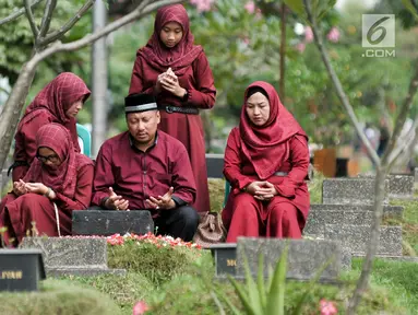 Umat Muslim berdoa saat ziarah kubur di Tempat Pemakaman Umum (TPU) Karet Bivak, Jakarta, Minggu (25/6). Hari pertama Lebaran, sejumlah warga memadati TPU untuk melangsungkan tradisi ziarah usai salat Idul Fitri. (Liputan6.com/Yoppy Renato)