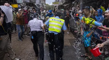 Orang-orang yang bersuka ria memercikkan air ke petugas polisi saat perayaan festival Songkran di Hong Kong, Minggu, 9 April 2023. (AP Photo/Louise Delmotte)