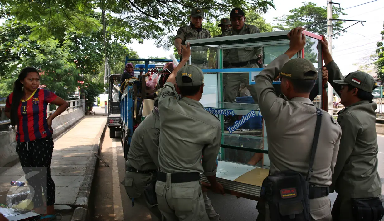 Seorang pedagang melihat gerobak dagangannya ditertibkan Petugas Satpol PP kelurahan Gelora ke atas mobil di pinggir jalan Kawasan Palmerah, Jakarta, Senin (17/10). (Liputan6.com/Johan Tallo)