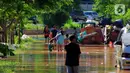 Sejumlah anak didampingi orang tua memanfaatkan banjir untuk bermain air menggunakan kolam ban kecil di Jalan Raya Kayu Putih, Jakarta, Minggu (23/2/2020). (merdeka.com/Magang/Muhammad Fayyadh)
