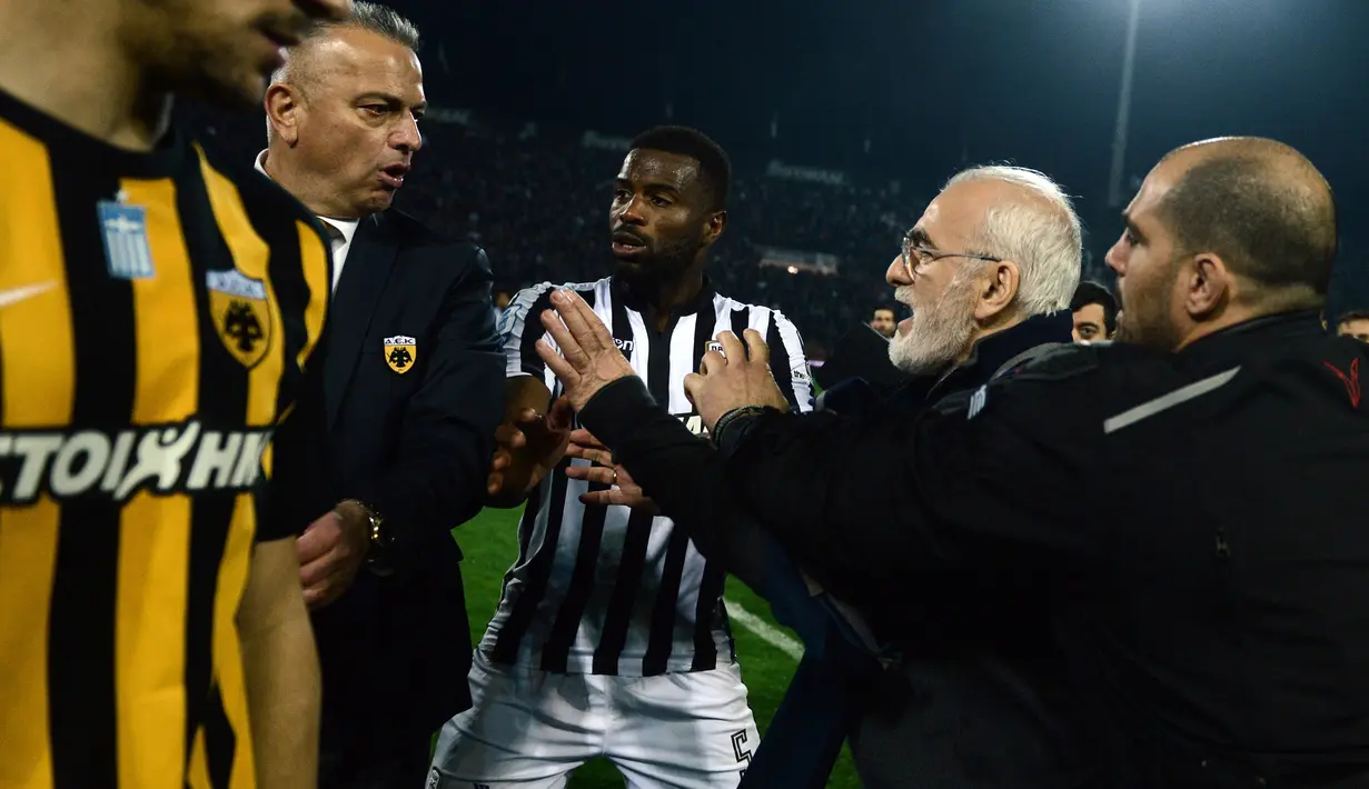 Presiden PAOK Ivan Savvidis yang membawa pistol memaki salah satu ofisial laga saat Liga Super Yunani kontra AEK Athens di Stadion Toumbas, Minggu (11/3). Pria 58 tahun itu pun dikawal oleh pengawal pribadinya ke luar lapangan. (InTime Sports via AP)
