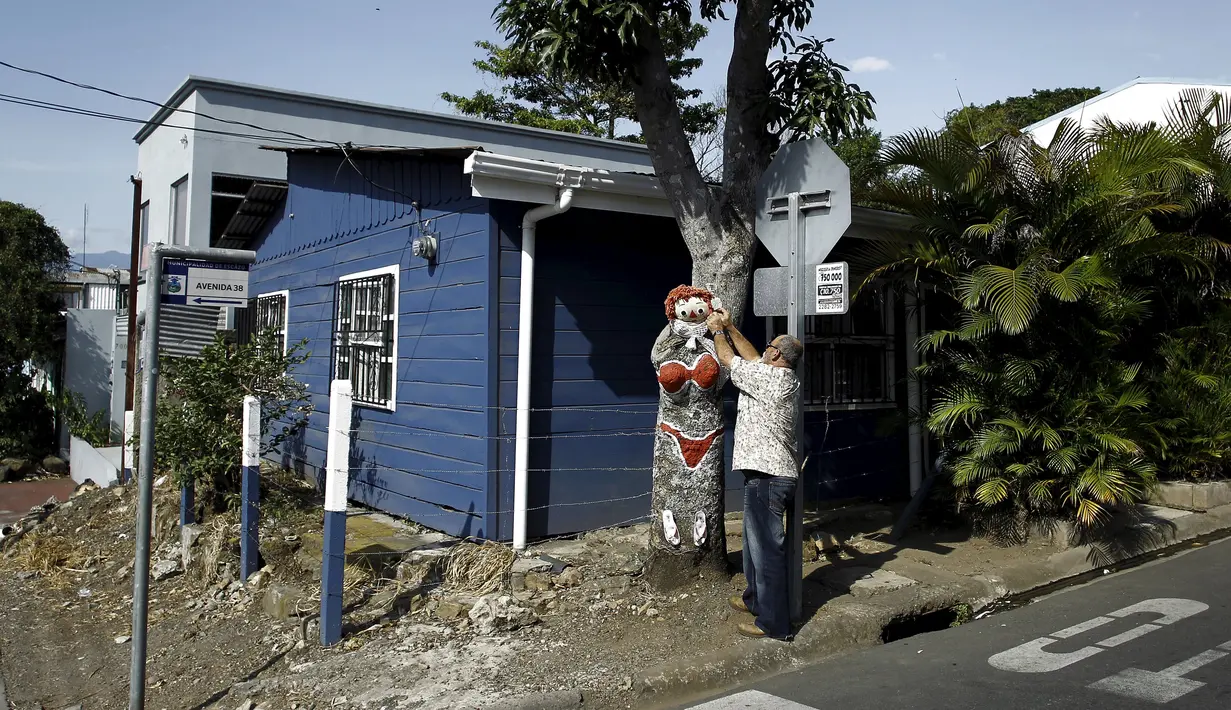 Gonzalo Sanchez menyelesaikan lukisan di pohon mangga yang diberi nama "The Woman in Red Bikini", di sudut jalan di lingkungan Escazu, Kosta Rika, Selasa (1/3). Lukisan itu menirukan sosok seorang wanita yang mengenakan bikini. (REUTERS/Juan Carlos Ulate)