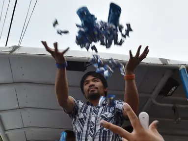  Mantan petinju Filipina, Manny Pacquiao melempar baju dan permen untuk pendukung selama kampanye di kota Calamba, Provinsi Laguna, selatan Manila (28/4). Manny Pacquiao akan ikut  pemilihan menjadi senat Filipina. (AFP PHOTO/TED aljibe)