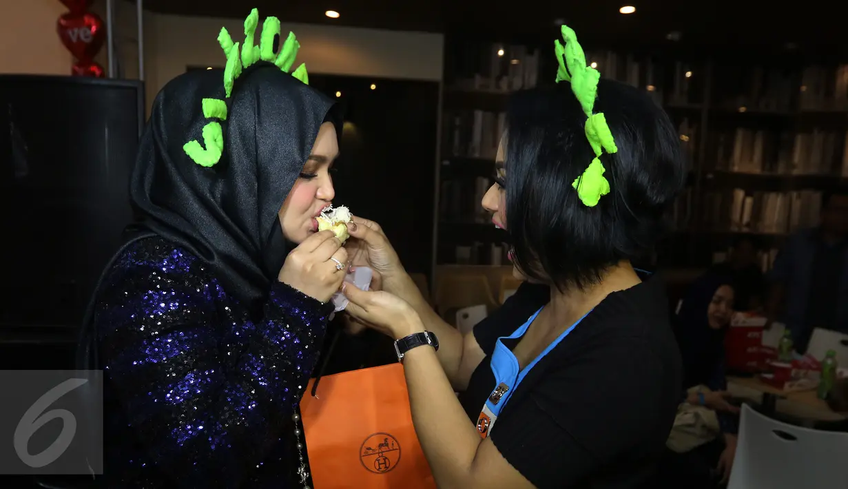 Krisdayanti menyuapi potongan kue ke Siti Nurhaliza saat perayaan ulang tahun sang Diva asal Malaysia di restoran cepat saji di Kemang, Jakarta, Minggu (10/1). Pelantun tembang Cindai ini berulang tahun pada 11 Januari. (Liputan6.com/Herman Zakharia)