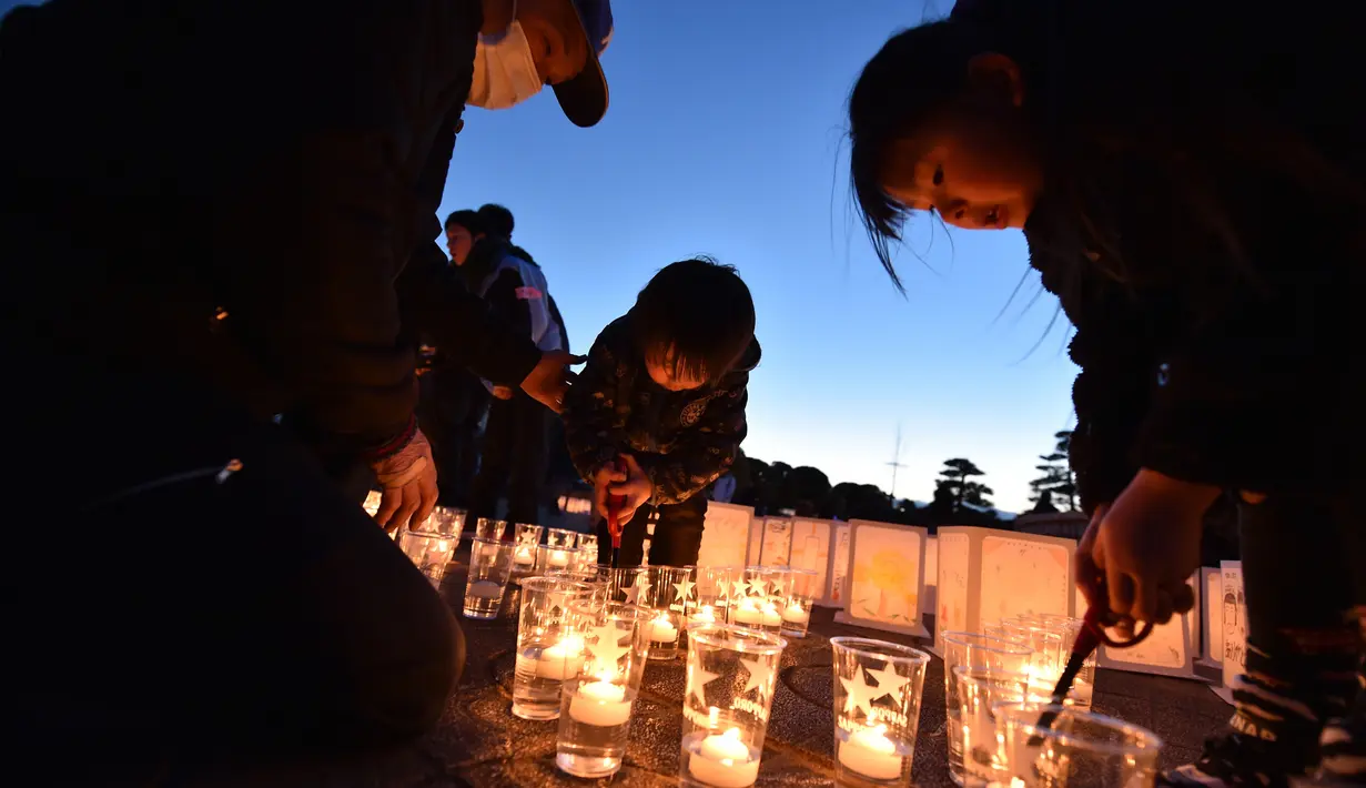Sebuah keluarga menyalakan lilin dalam upacara peringatan bencana gempa tsunami di Natori, Prefektur Miyagi, Jepang (11/3). Masyarakat Jepang memperingati enam tahun gempa dan tsunami yang terjadi pada 2011 lalu. (AFP/Kazuhiro Nogi)
