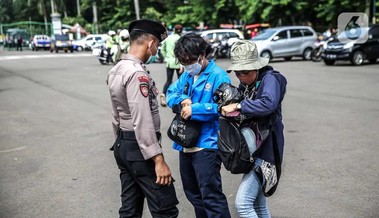Polisi memeriksa barang bawaan mahasiswa yang akan berunjuk rasa di Patung Kuda, Jakarta, Selasa (20/10/2020). Pemeriksaan tersebut dilakukan untuk memastikan unjuk rasa berjalan aman dan damai. (Liputan6.com/Faizal Fanani)