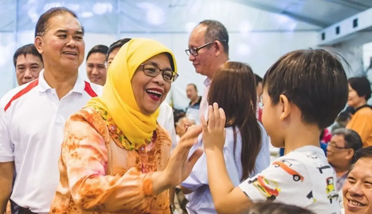 Halimah Yacob saat tos kepada seorang anak pada Festival Hantu Lapar yang dihadiri 4000 tamu undangan di Kuil Sheng Hong, Singapura (08/9). (instagram.com/halimahyacob)