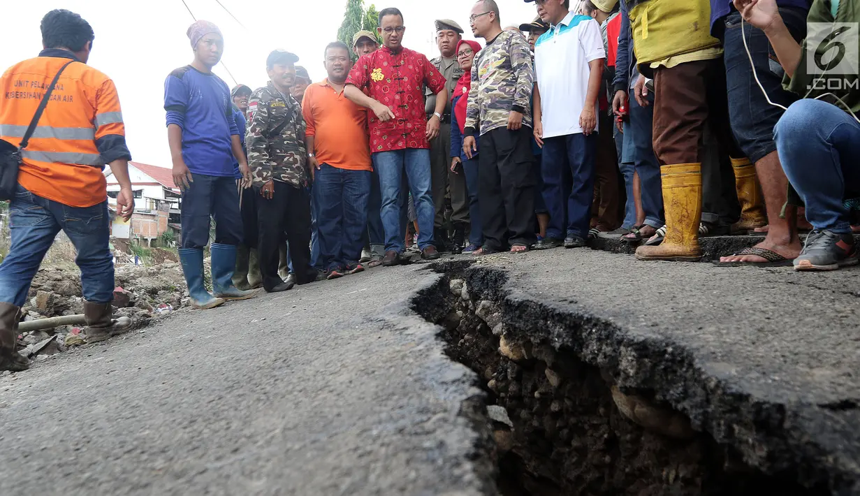 Gubernur DKI Anies Baswesdan meninjau lokasi jalan retak di  Kelurahan Kebon Manggis, Kecamatan Matraman, Jakarta Timur, Jumat (16/2). Kehadiran Anies yang mengenakan baju tradisional China itu mengundang perhatian warga sekitar (Liputan6.com/Johan Tallo)