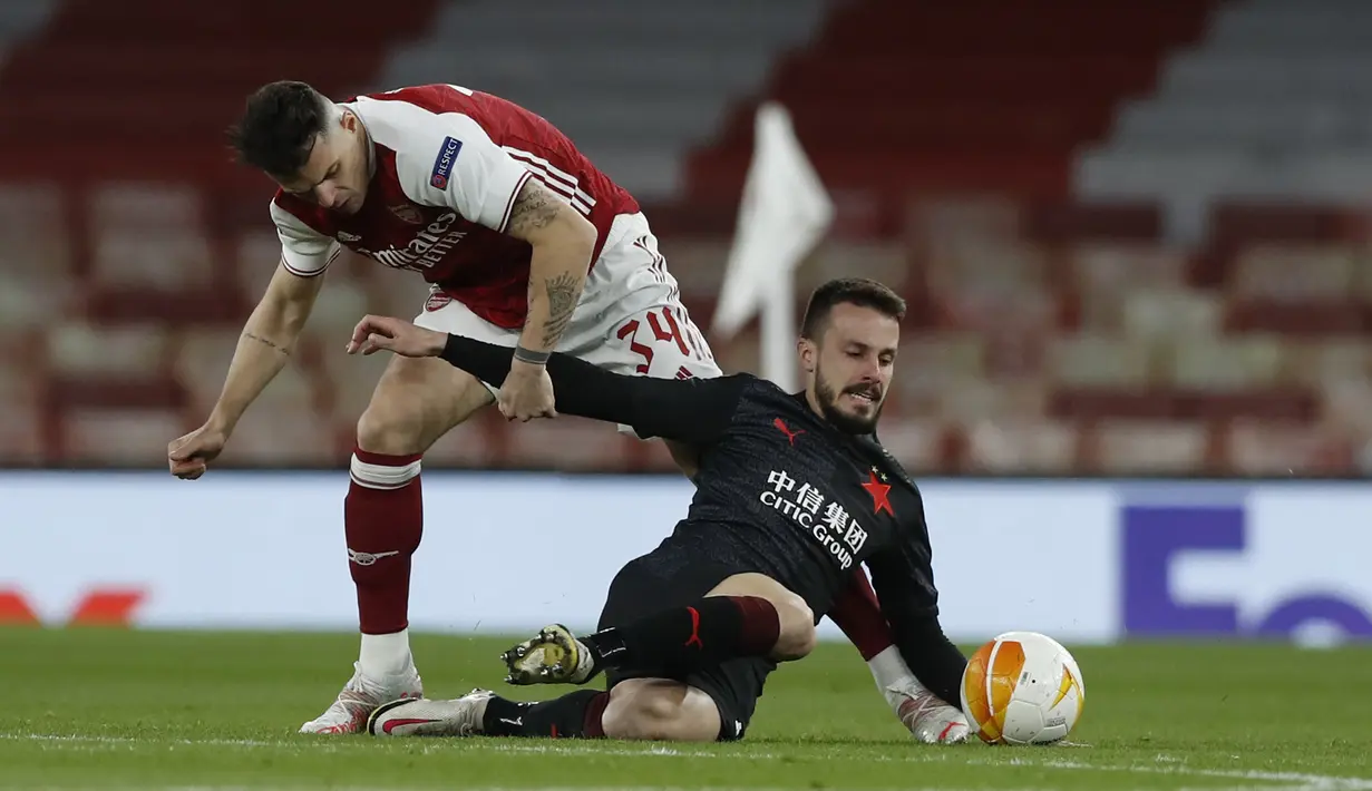 Gelandang Arsenal, Granit Xhaka (kiri) menghentikan pergerakan gelandang Slavia Praha, Jakub Hromada dalam laga leg pertama perempatfinal Liga Europa 2020/2021 di Emirates Stadium, London, Kamis (8/4/2021). Arsenal bermain imbang 1-1 dengan Slavia Praha. (AP/Alastair Grant)