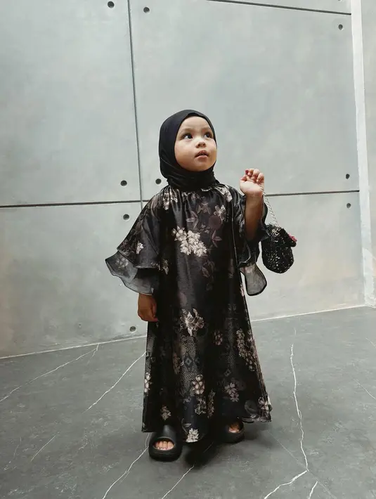 Penampilan manis lucu dan santun ala Ameena ini menggunakan gamis hitam bermotif flora yang cantik. [Foto: Instagram/ameenaatta]