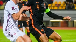 Pemain Latvia Kaspars Dubra (kiri) berebut bola dengan pemain Belanda Virgil van Dijk pada pertandingan sepak bola kualifikasi Grup G Piala Dunia 2022 di Stadion Daugava, Riga, Latvia, 8 Oktober 2021. Belanda menang 1-0. (Gint Ivuskans/AFP)