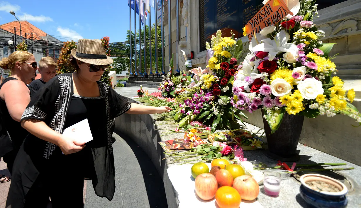 Wisatawan asing menaburkan bunga di Monumen Ground Zero Bali di kawasan Kuta, Bali (12/10). Mereka datang dan menaburkan bunga untuk memperingati tragedi bom Bali 2002. (AFP Photo/Sonny Tumbelaka)