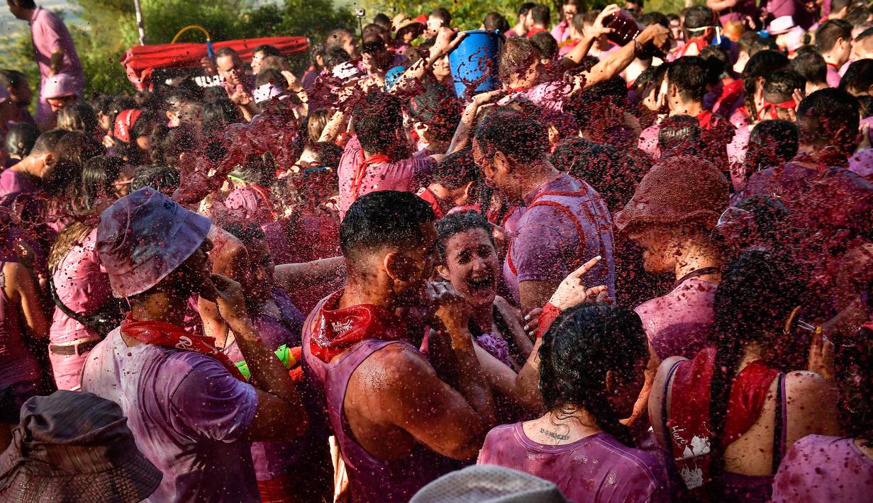 Orang-orang bersuka ria dalam perang anggur di Haro, Spanyol utara, Sabtu (29/6/2019). Setiap peserta wajib mengenakan pakaian putih pada festival yang diselenggarakan rutin setiap bulan Juni di kota Haro, yang terkenal sebagai produsen anggur tersebut. (AP/Alvaro Barrientos)