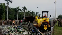 Operator alat berat memusnahkan ribuan botol minuman beralkohol ilegal hasil penertiban Januari-Juni 2016, di kawasan Monas, Jakarta, Selasa (28/6). Sebanyak 19.628 botol yang antara lain hasil penertiban di kawasan Kalijodo. (Liptan6.com/Gempur M Surya)