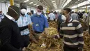 Para juru lelang mengenakan masker agar terhindar dari virus corona COVID-19 pada hari pertama musim perdagangan tembakau di Harare, Zimbabwe, Rabu (29/4/2020). Musim perdagangan tembakau kali ini dimulai dari lantai lelang yang mematuhi aturan ketat akibat COVID-19. (AP Photo/Tsvangirayi Mukwazhi)