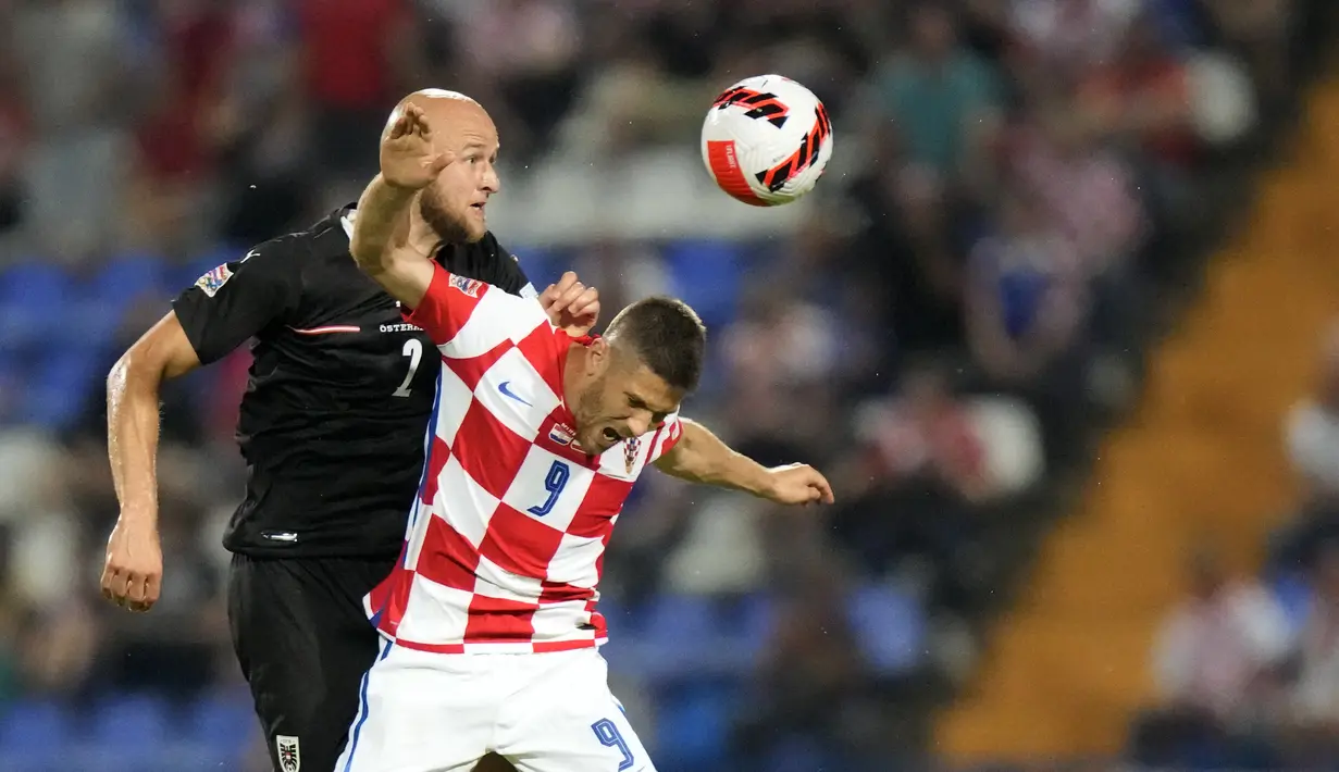 Penyerang timnas Kroasia Andrej Kramaric melompat saat berebut bola dengan bek Austria Gernot Trauner pada matchday pertama UEFA Nations League A Grup 1 di Stadion Gradski Vrt, Sabtu (4/6/2022) dinihari WIB. Ralf Rangnick sukses debut dengan mengantarkan Timnas Austria menang telak atas Kroasia dengan skor 3-0. (AP Photo/Darko Bandic)