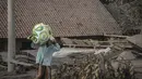 Seorang warga menyelamatkan barang-barangnya di area yang tertutup abu vulkanik setelah letusan gunung Semeru di desa Sumber Wuluh di Lumajang, Jawa Timur, Minggu (5/12/2021). (AFP /Juni Kriswanto)