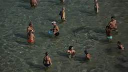 Orang-orang mendinginkan diri di air pantai Arpoador selama gelombang panas di Rio de Janeiro, Brasil, pada hari libur kota Saint Sebastian, Kamis (20/1/2022). (AP Photo/Bruna Prado)
