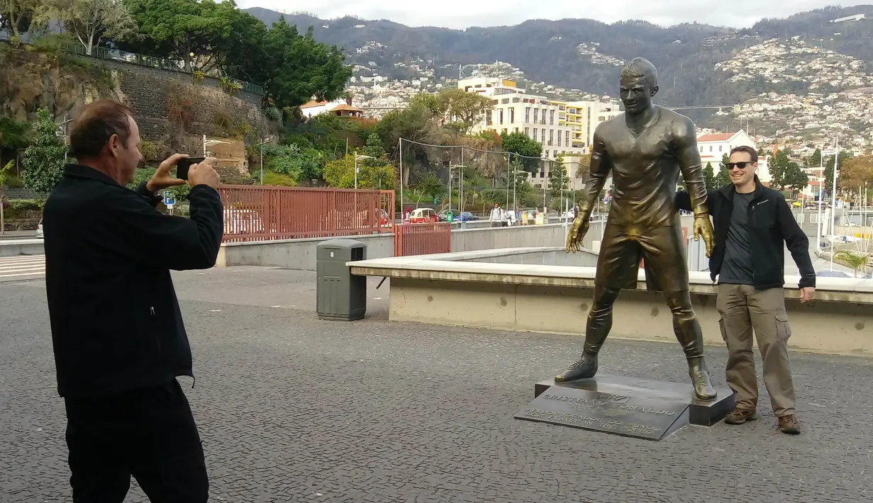 Seorang pengunjung foto bersama patung Cristiano Ronaldo di Museum CR 7. Museum ini terdapat di Kota Funchal, tempat Ronaldo lahir dan tunbuh besar. (Bola.com/Reza Khomaini)