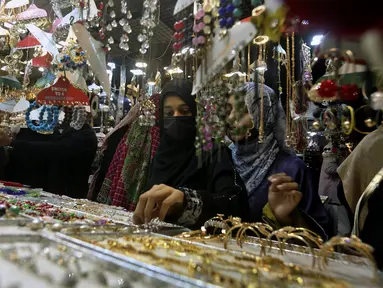 Gadis-gadis muda melihat-lihat perhiasan buatan tradisional saat dia dan yang lainnya mengunjungi pasar untuk berbelanja perayaan Idul Fitri mendatang, di Karachi, Pakistan, Jumat, 29 April 2022. Idul Fitri menandai akhir bulan suci Ramadhan. (AP Photo/Fareed Khan)
